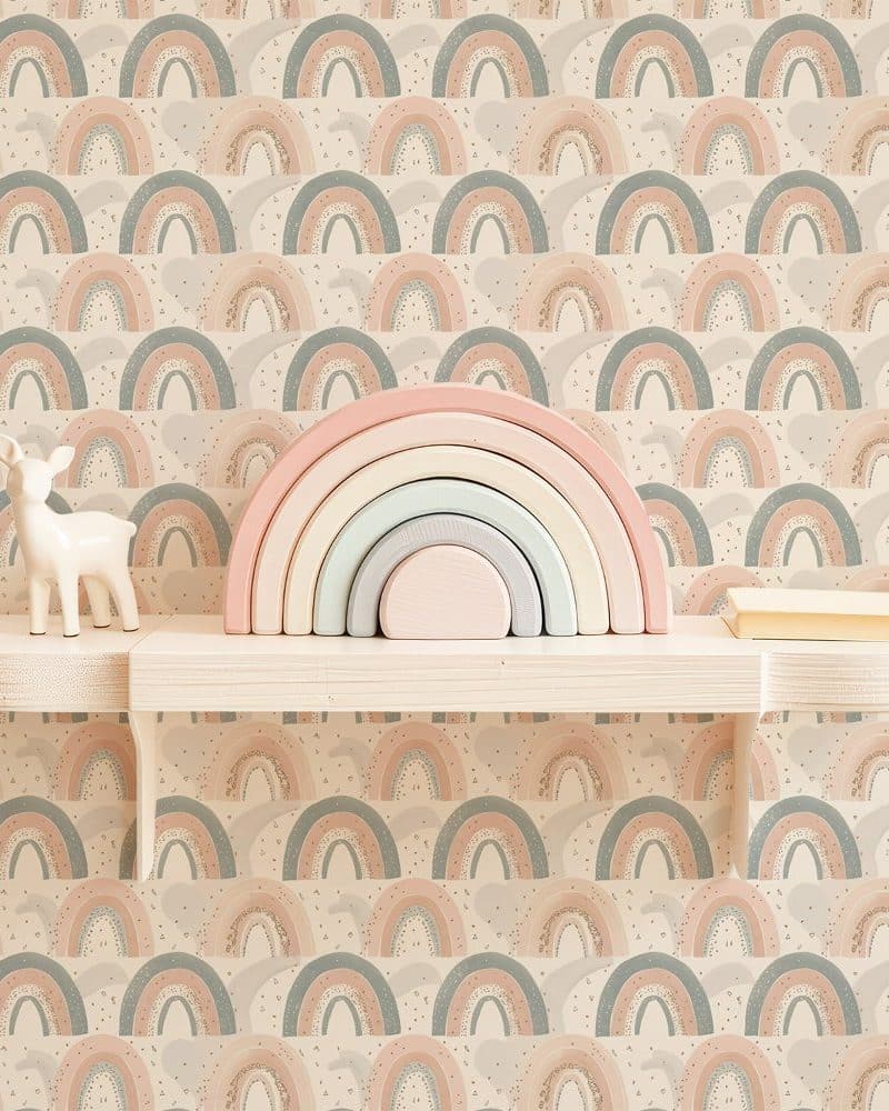 Pastel rainbow stacking toy and small deer figurine on a shelf against a rainbow patterned wall.