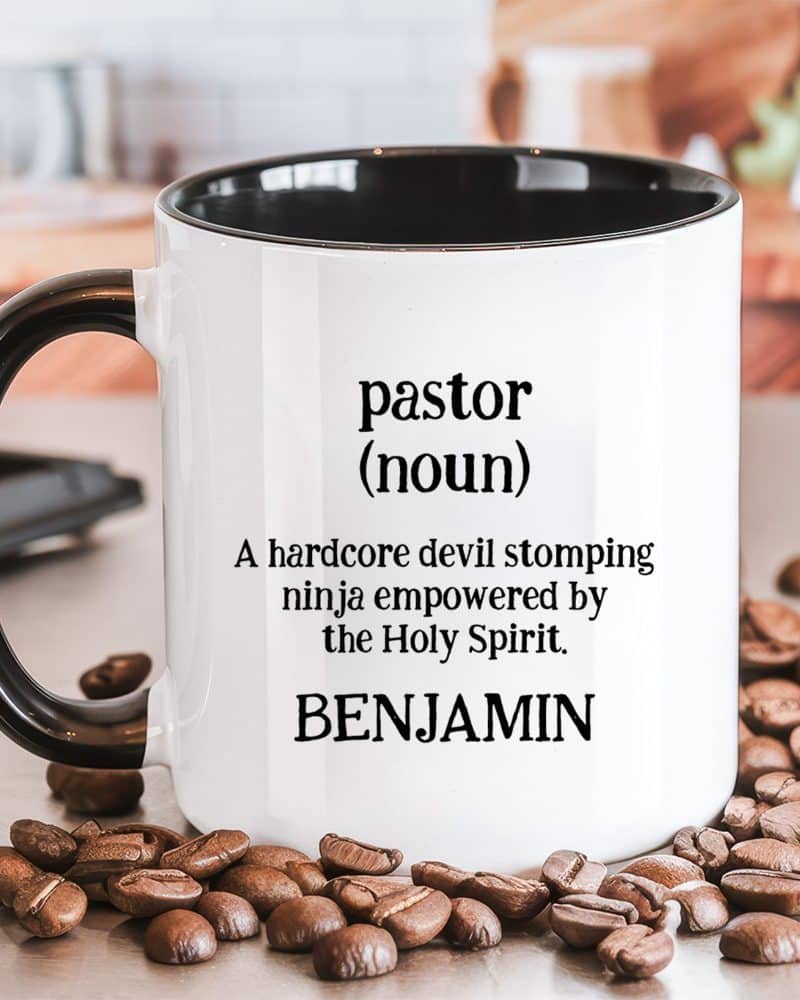 White coffee mug with black handle and interior, displaying a humorous definition of pastor, personalized with the name Benjamin.