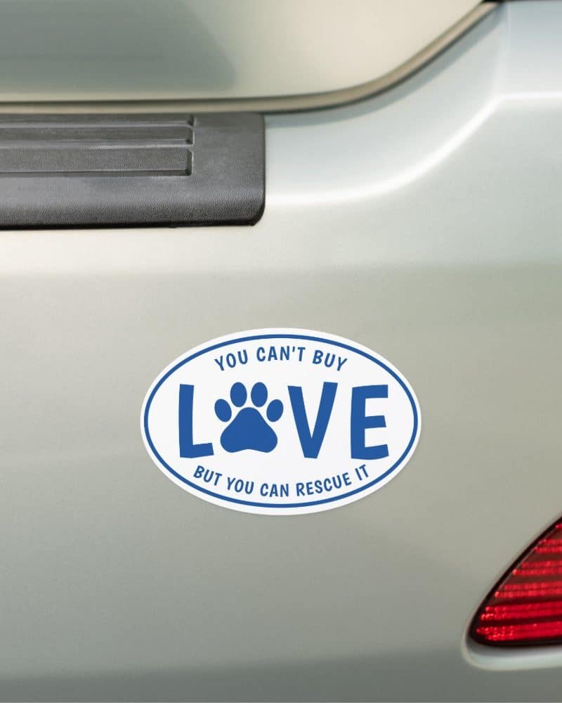 Oval car magnet with the words You Can't Buy Love, but you can rescue it. A paw print is centered in the word Love.