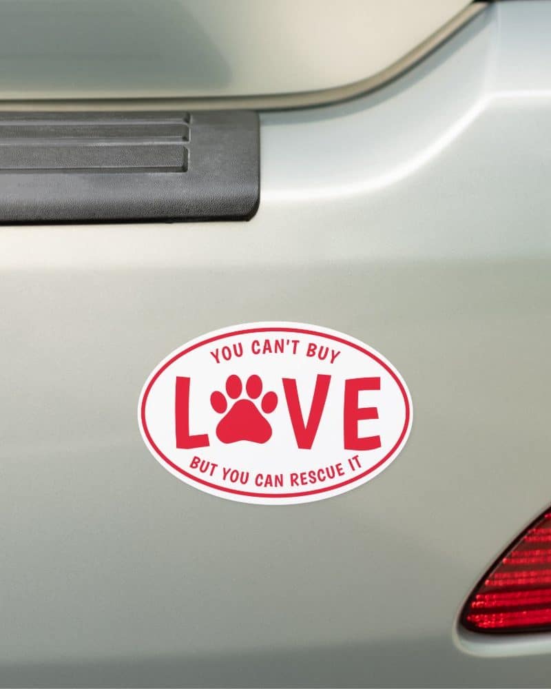 Oval car magnet with red text and paw print that says You Can't Buy Love but You Can Rescue It.
