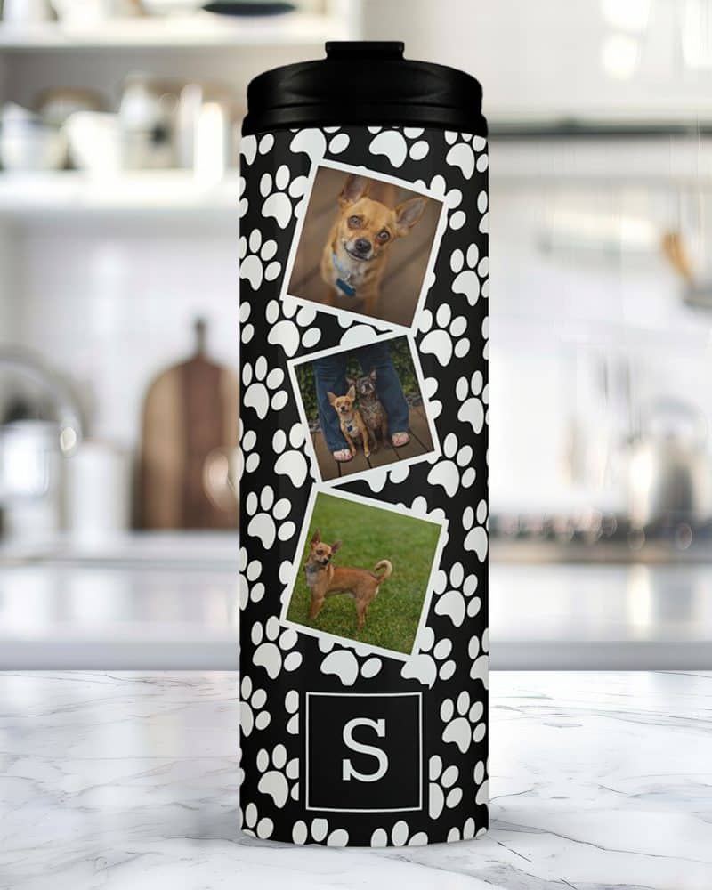 Travel mug with black paw print design, featuring three photos of small dogs and a monogram.