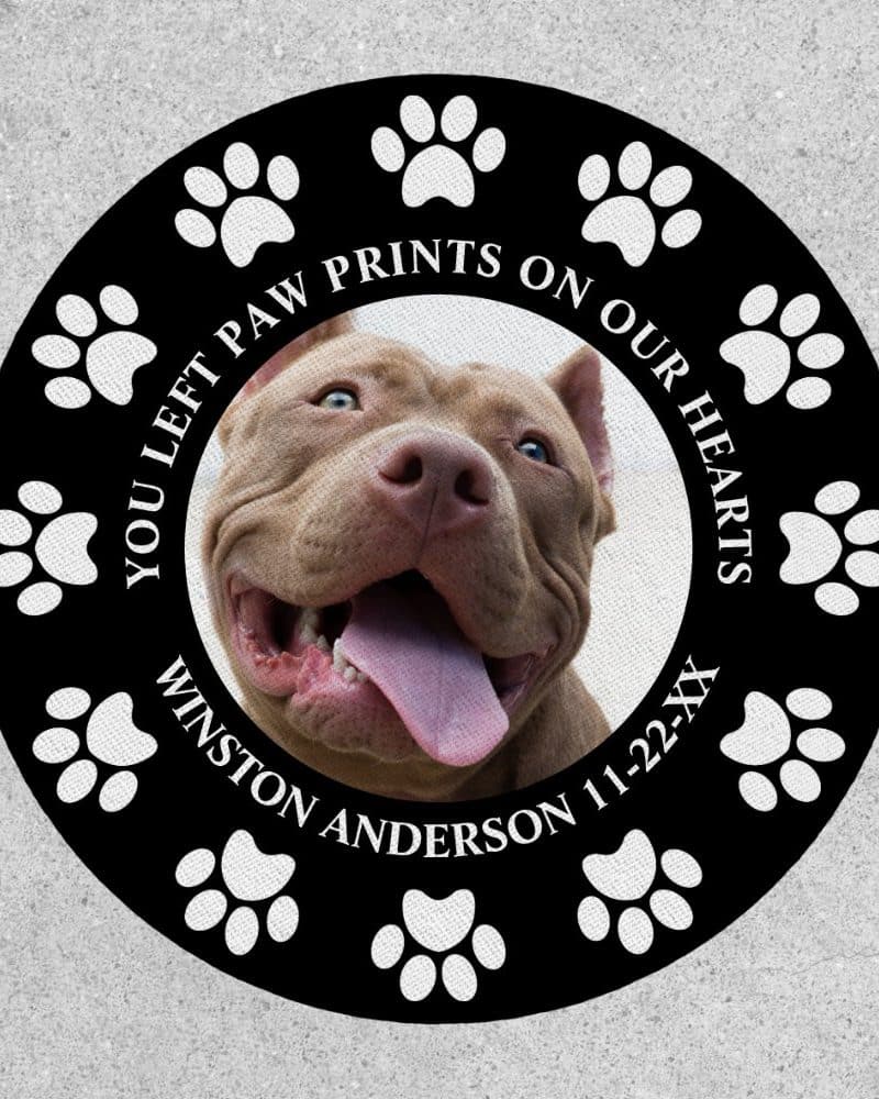 Black circle with white paw prints and a photo of a smiling brown Pit Bull. Text reads: You left paw prints on our hearts, Winston Anderson 11-22-XX.