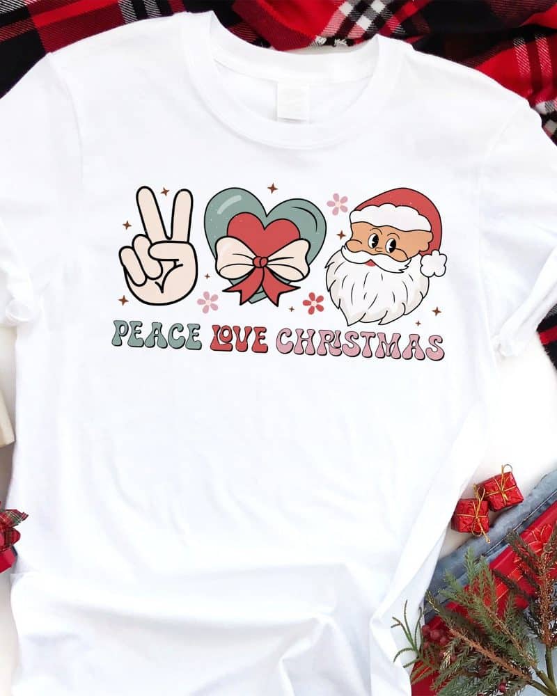 White t-shirt with a peace sign, heart, Santa face, and the text Peace Love Christmas.