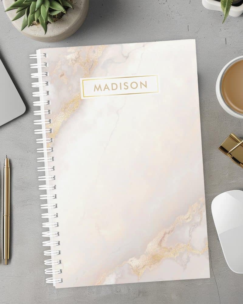 Spiral-bound notebook with a marble cover and the name Madison in gold lettering.