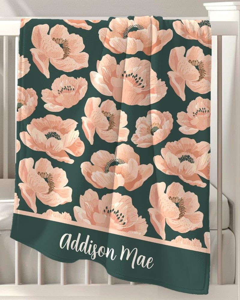 Personalized baby blanket with a dark teal background and a repeating pattern of peach-colored anemones. The name Addison Mae is embroidered at the bottom.