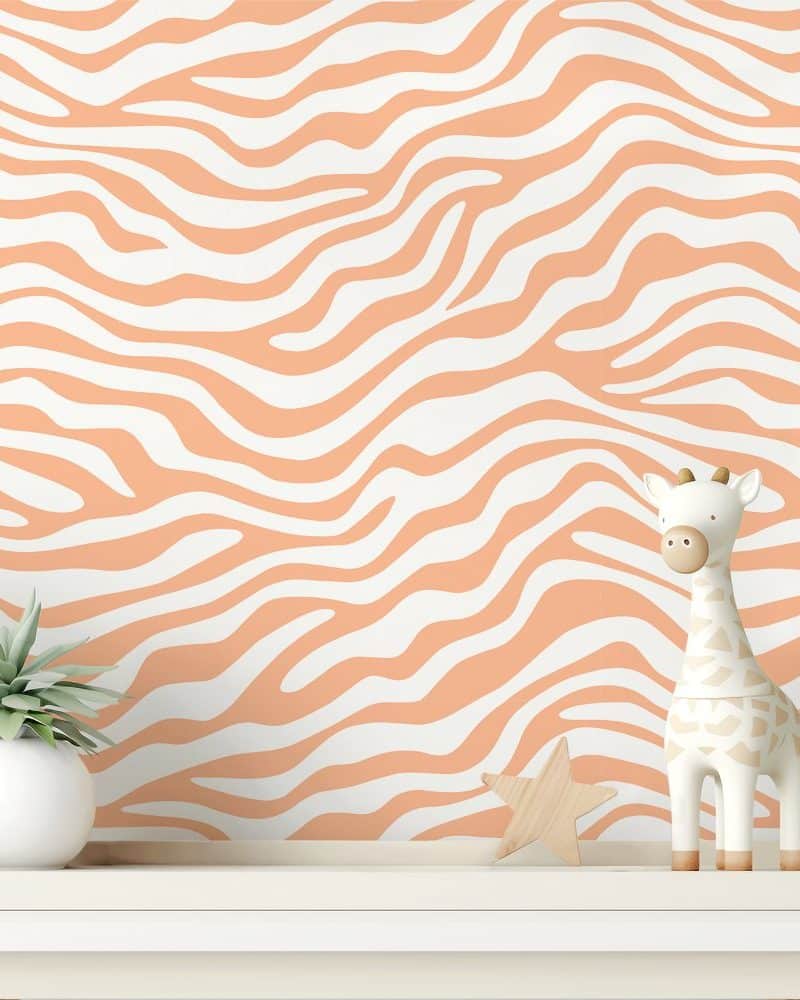 A peach-colored zebra-striped wall with a small giraffe figurine and a succulent plant on a white shelf.