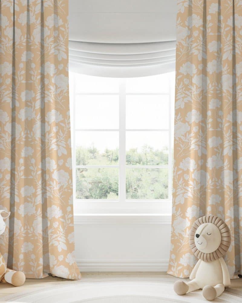 Beige curtains with a white floral pattern hang on a window.