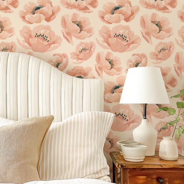 A Bed With A Striped Headboard And Pillows Sits Against A Wall Covered In A Peach-Colored Poppy Floral Wallpaper.