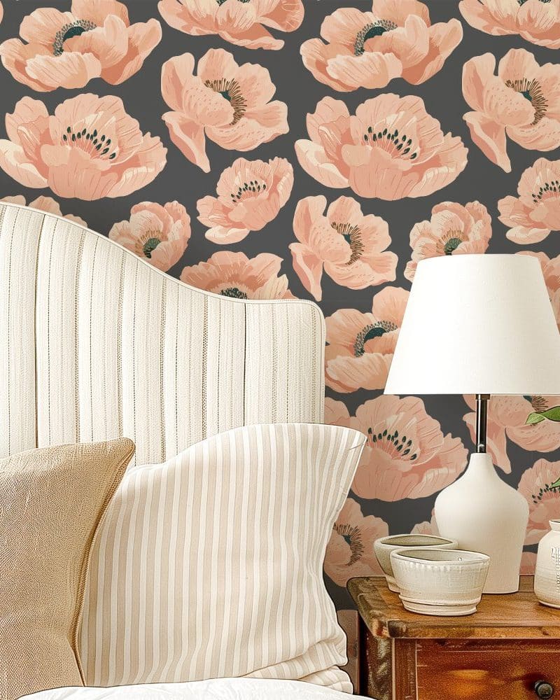 A bed with beige striped pillows against a wall with a floral wallpaper featuring peach-colored poppies on a dark gray background.