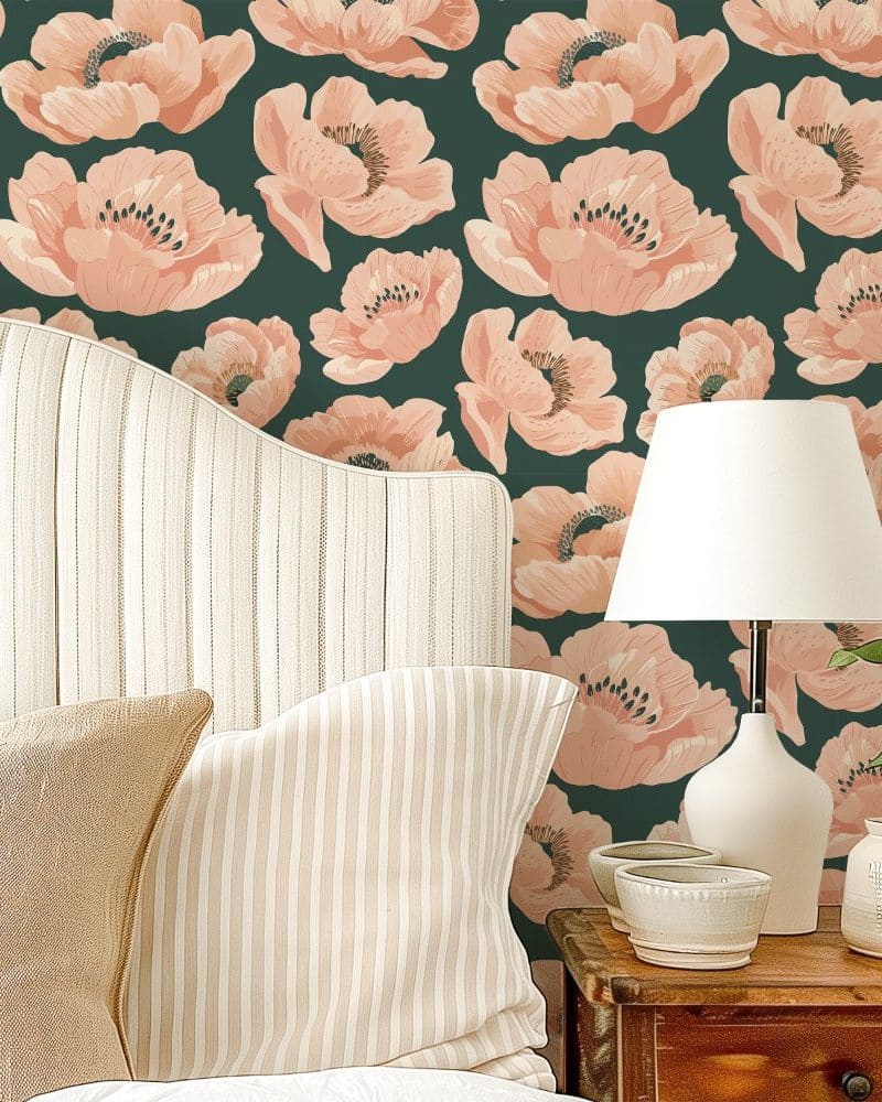 A bedroom headboard and pillows against a wall with a dark green floral wallpaper featuring large peach-colored poppies.