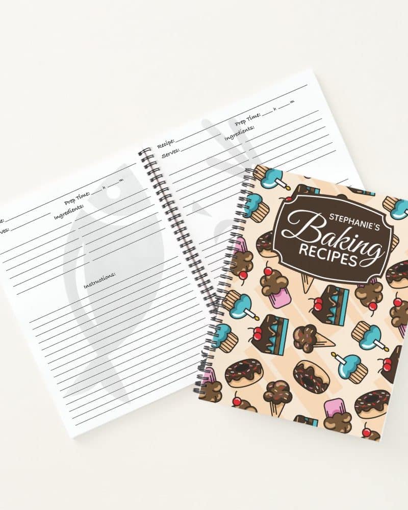 Spiral-bound baking recipe book with a light beige cover featuring illustrated cupcakes, ice cream cones, and cakes. The book is titled Stephanies Baking Recipes.