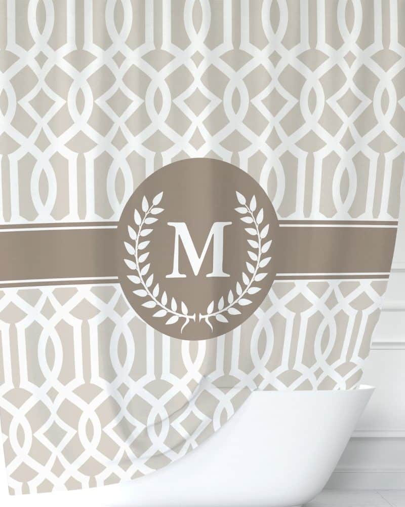 Beige shower curtain with a geometric pattern and a brown circle monogram featuring the letter M.
