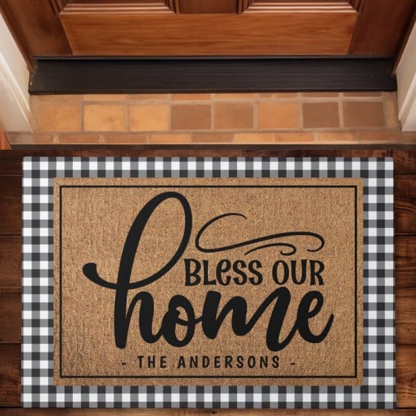 Brown Coir Doormat With Black Lettering That Says Bless Our Home And The Andersons Name Below. The Doormat Has A Black And White Checkered Border.