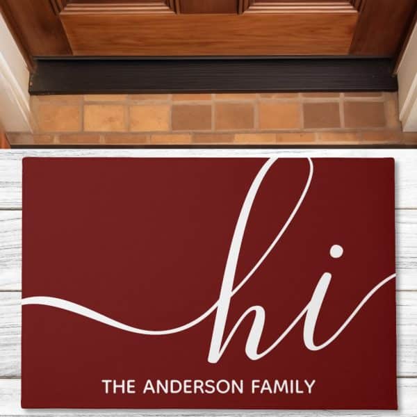Burgundy Doormat With The Word Hi In A Stylized Script Font And The Anderson Family Below.