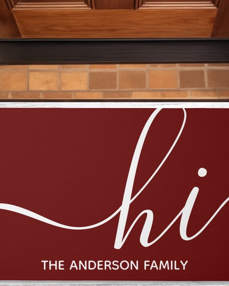 Burgundy doormat with the word hi in a stylized script font and The Anderson Family below.