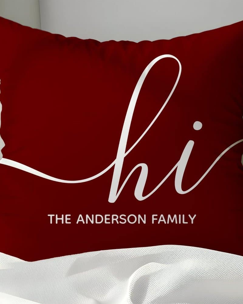 Burgundy throw pillow with white script lettering that says hi and The Anderson Family below.