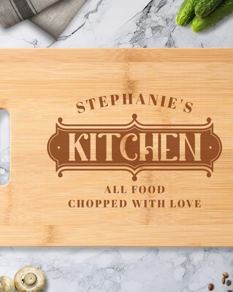 Personalized bamboo cutting board with the words Stephanie's Kitchen and All Food Chopped With Love engraved on it.