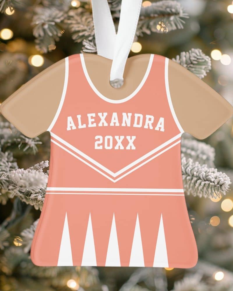 Coral and beige cheerleader uniform-shaped Christmas ornament with the name Alexandra and the year 20XX.