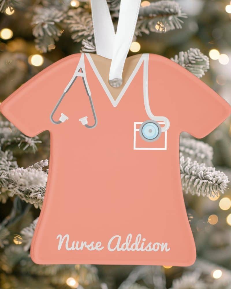 Peach-colored nurse scrubs ornament with stethoscope and name, Nurse Addison.