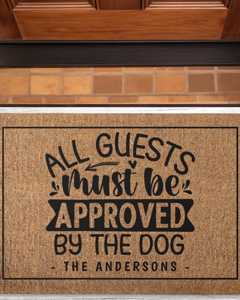 A tan coir doormat with black text that reads All Guests Must Be Approved By The Dog, and the name The Andersons.