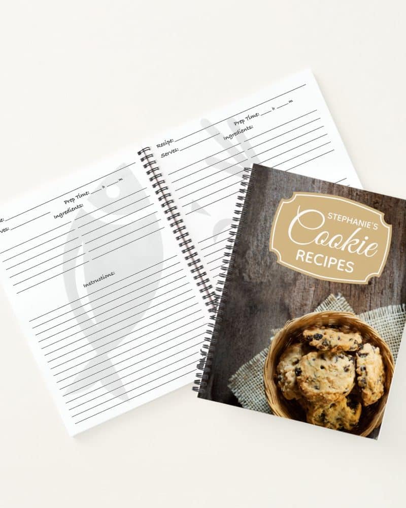 Spiral-bound blank recipe book next to a spiral-bound cookie recipe book with a photo of chocolate chip cookies.