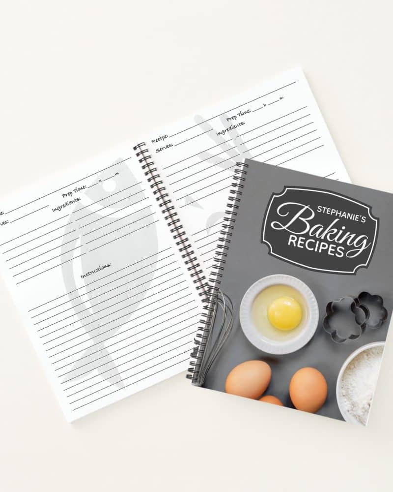 A spiral-bound baking recipe book with blank recipe pages lying open beside it.