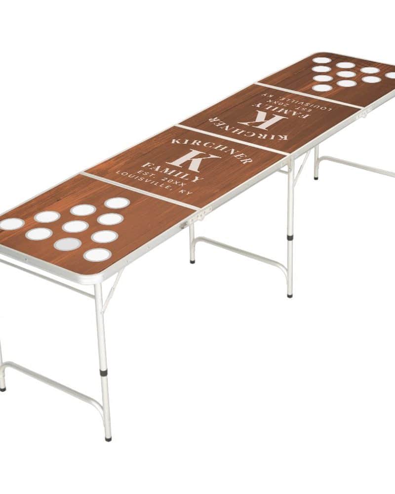 Personalized brown wood-grain beer pong table with a family name and initial.