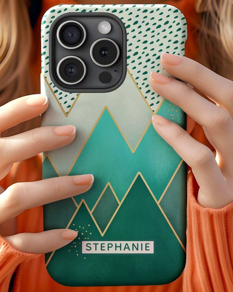 Close-up of hands holding a teal and gold iPhone case featuring a geometric mountain design and the name Stephanie.