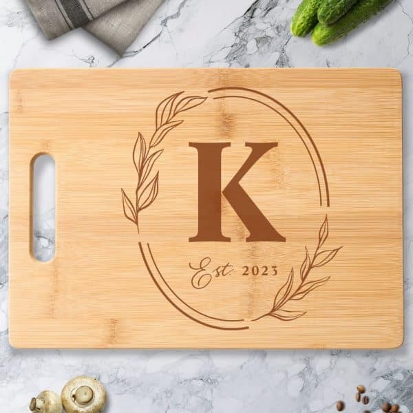 Light Brown Bamboo Cutting Board With A Brown Engraved Monogram Of The Letter K, Within A Wreath Design And The Text Est. 2023.