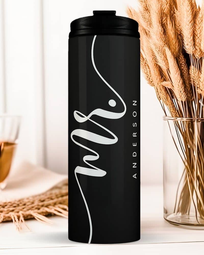 Black travel tumbler with the word Mrs and a last name, Anderson, in a stylized white script.