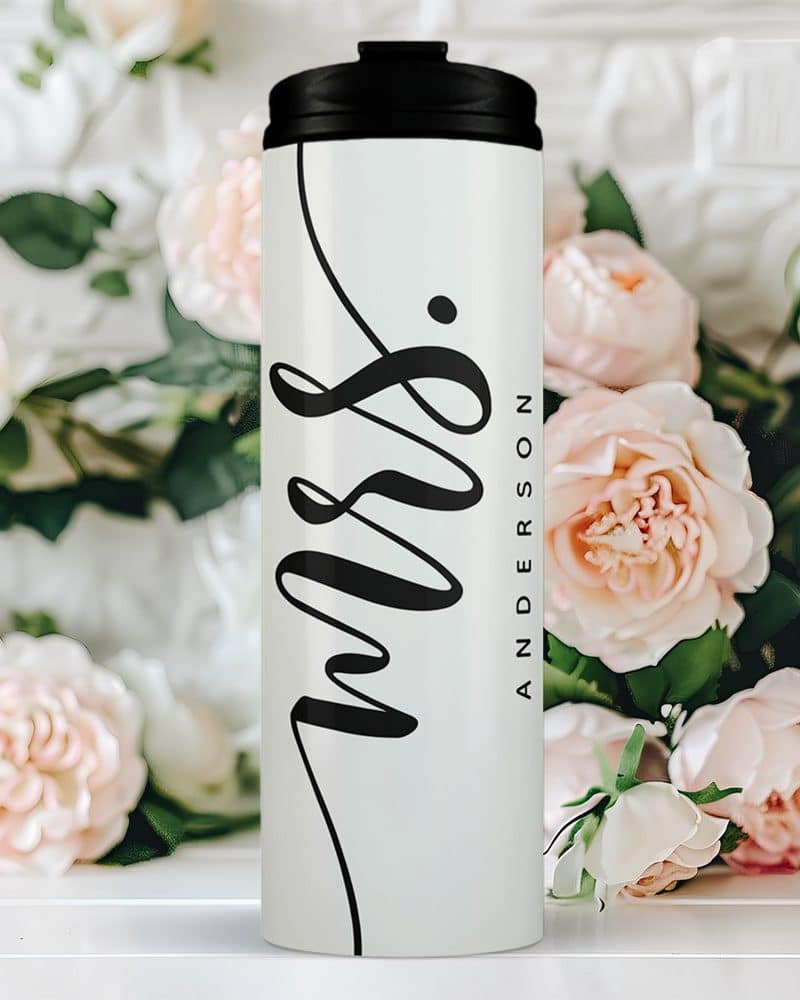 White travel mug with black lid and the word Mrs. and a name in elegant script.