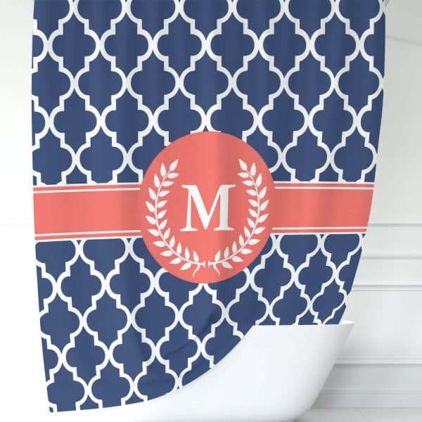 Navy Blue Shower Curtain With A White Quatrefoil Pattern, Coral Colored Band, And A Coral Circle Containing A White Laurel Wreath Surrounding The Letter M.
