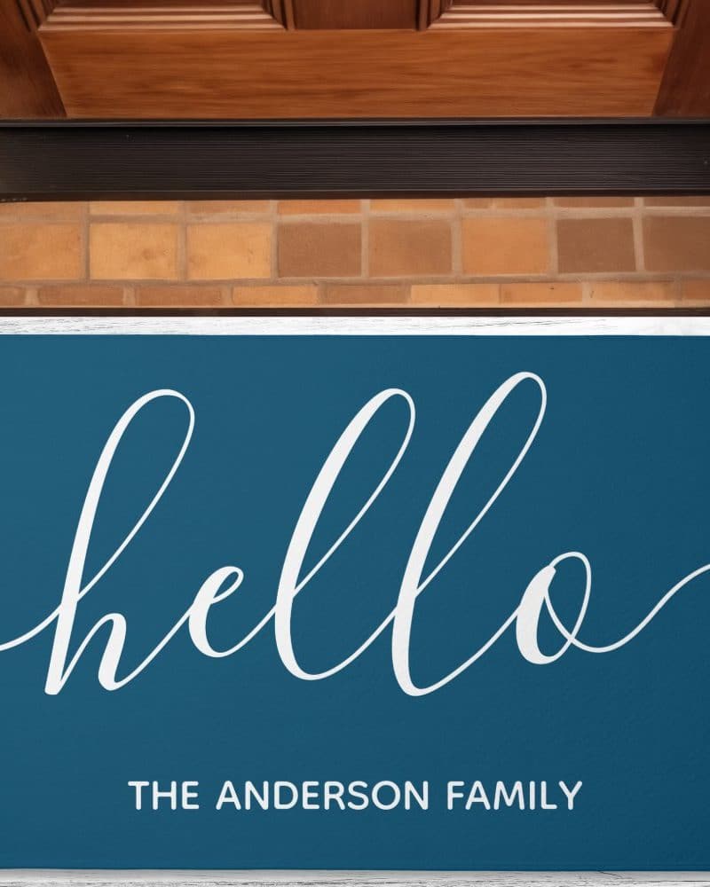 Teal welcome mat with the word hello in a white script font and the text The Anderson Family below.