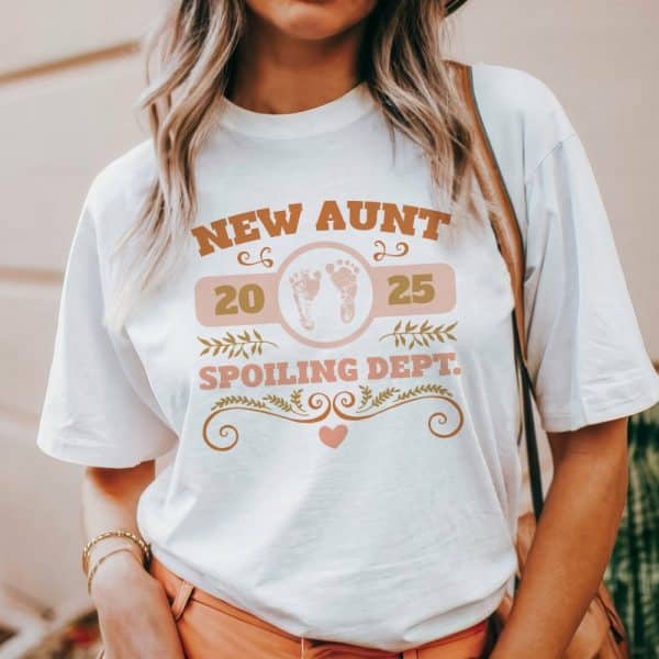 A White T-Shirt With A Design Announcing New Aunt 2025 Spoiling Dept., Featuring Baby Footprints.