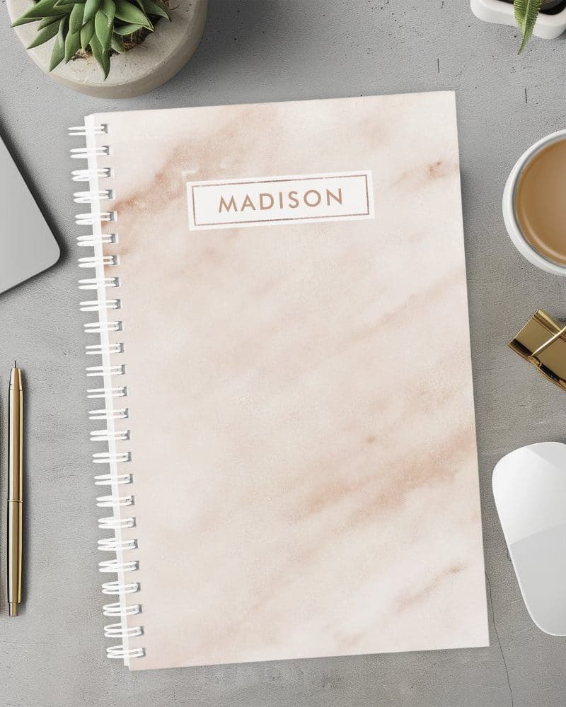 Spiral-bound notebook with a marble design and the name Madison on the cover.