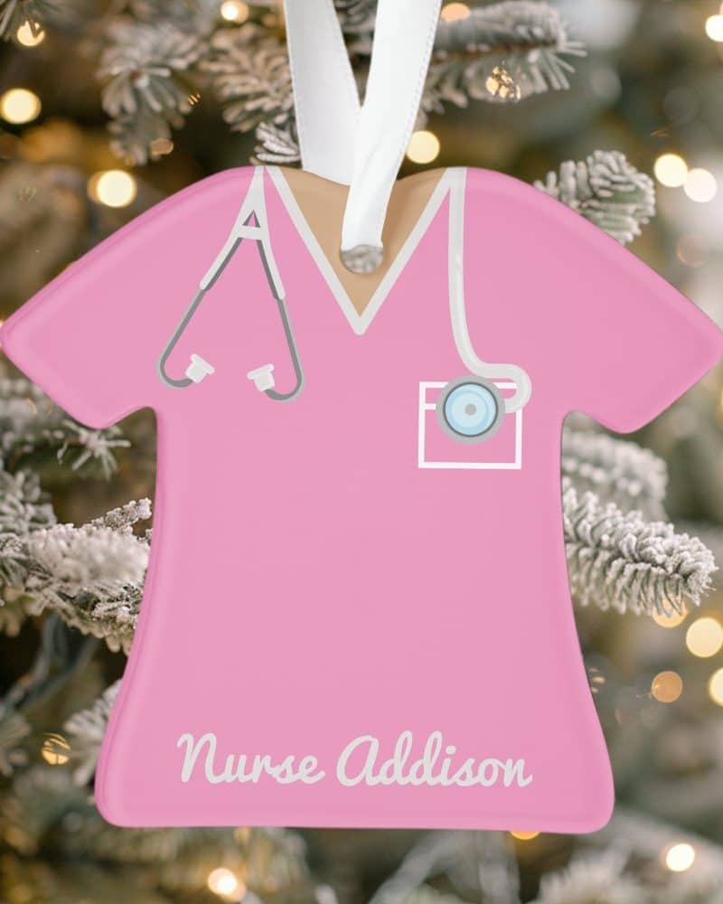 Pink nurse scrubs ornament with stethoscope and Nurse Addison inscribed at the bottom.