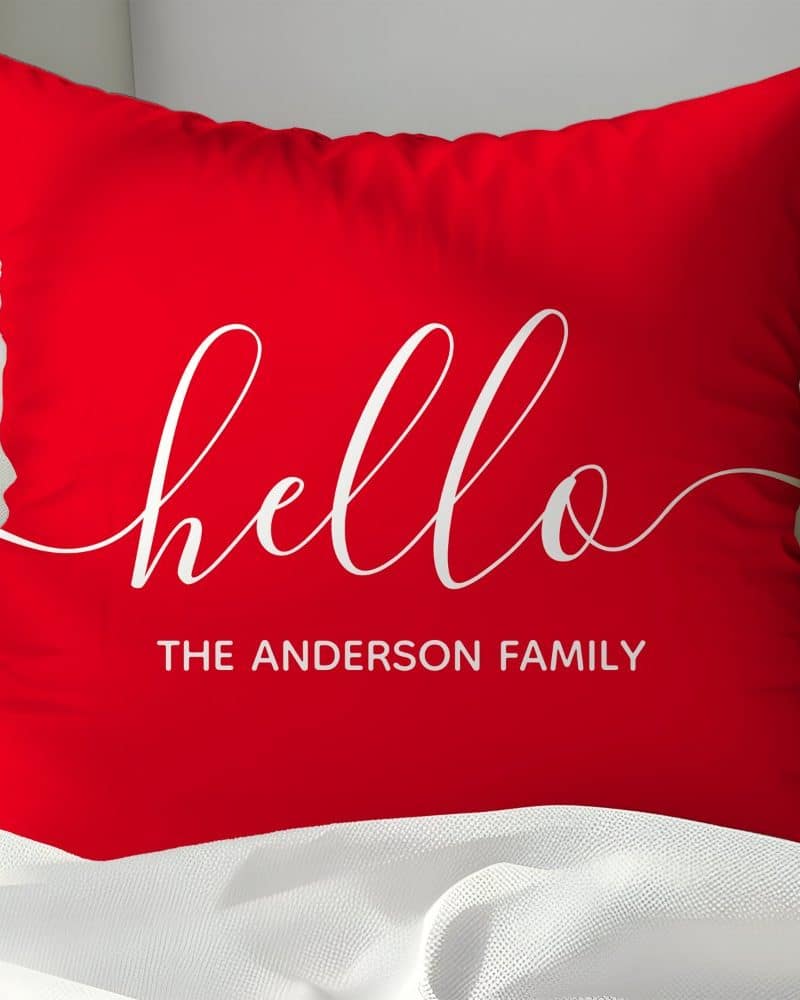 Red pillow with white cursive hello and The Anderson Family.