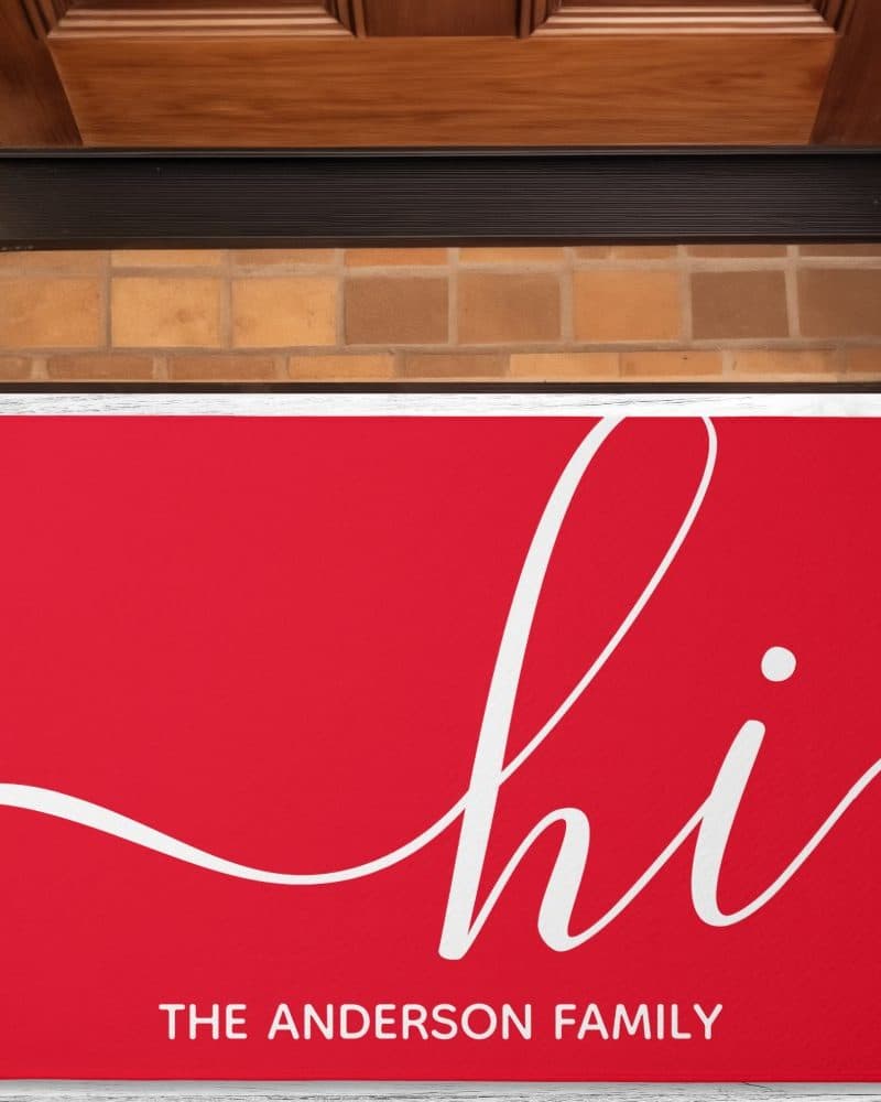 Red welcome mat with white cursive "hi" and "The Anderson Family" below.