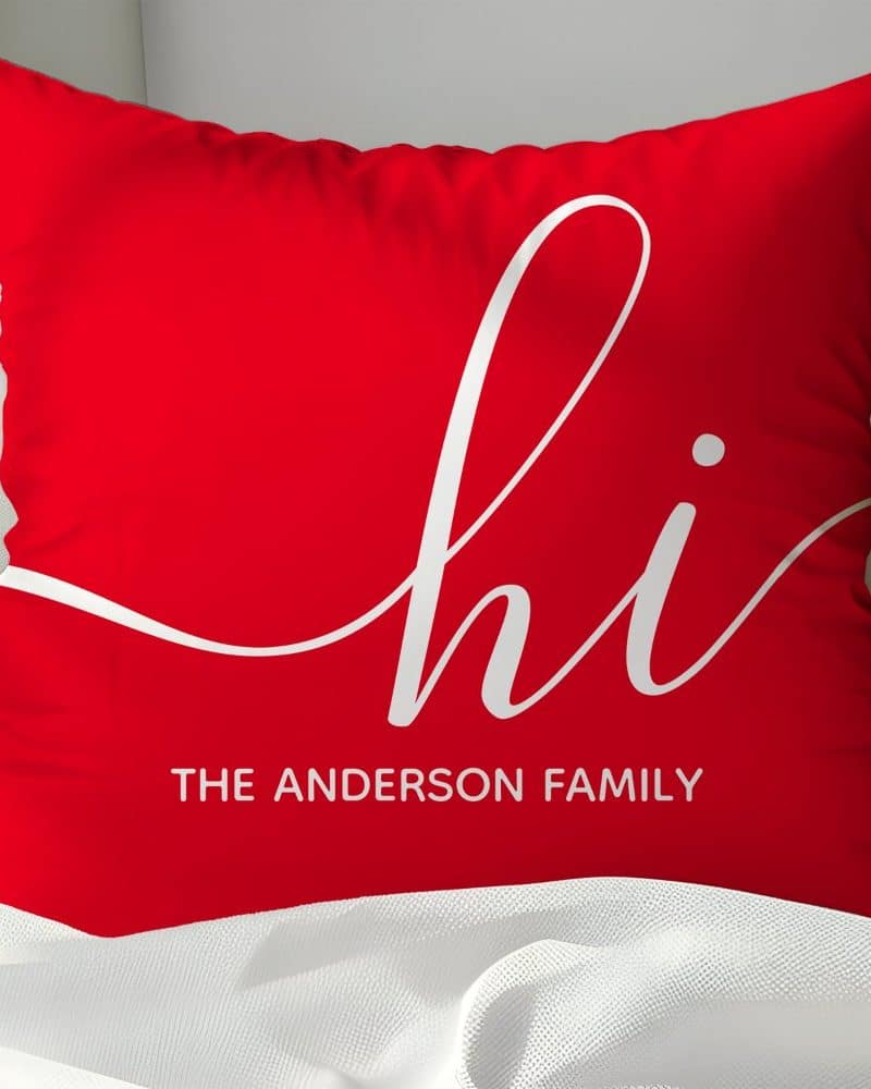 Red pillow with white cursive "hi" and "The Anderson Family" below.