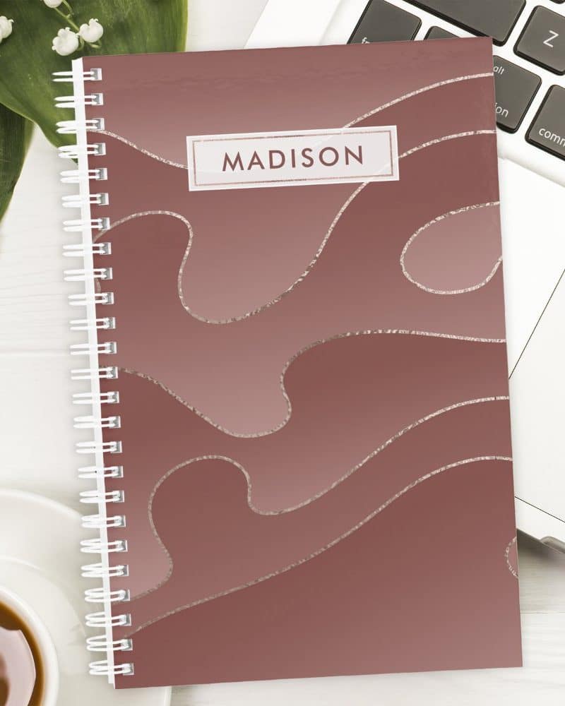 Spiral-bound notebook with a dusty rose cover featuring a metallic silver abstract design and the name Madison.