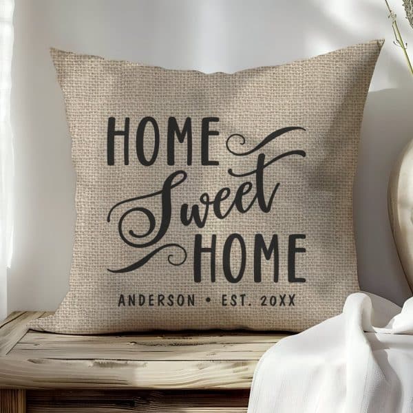 Beige Burlap Pillow With Black Text Reading Home Sweet Home And A Personalized Family Name And Establishment Year.