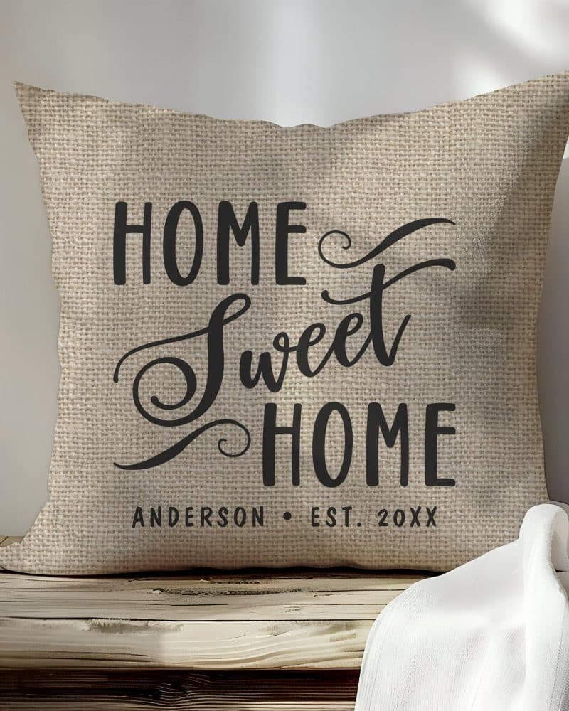 Beige burlap pillow with black text reading Home Sweet Home and a personalized family name and establishment year.
