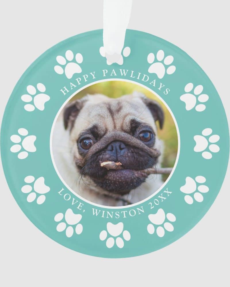 Teal circular ornament featuring a pug dog photo, surrounded by paw prints and the text Happy Pawlidays, Love, Winston 20XX.