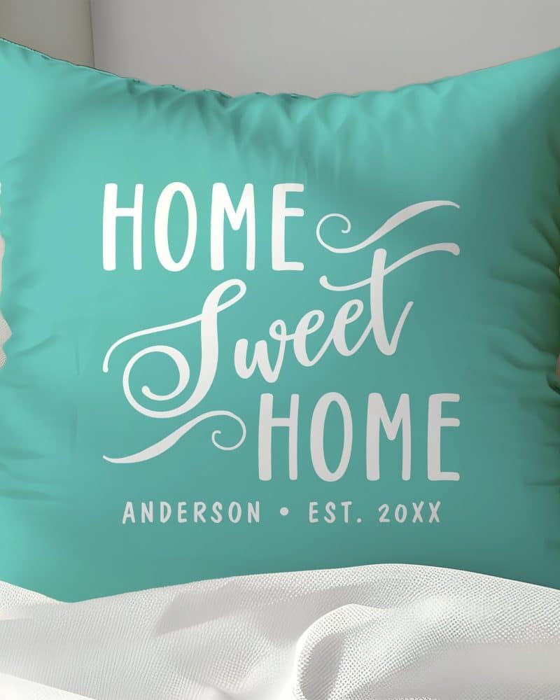 Teal pillow with the words Home Sweet Home in white script lettering. A family name and establishment year are also visible at the bottom.
