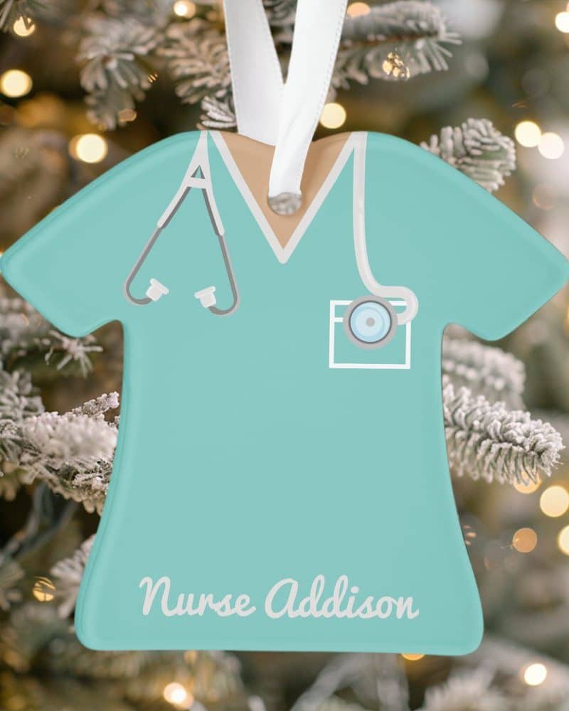 Teal nurse scrubs-shaped Christmas ornament with the name Addison.