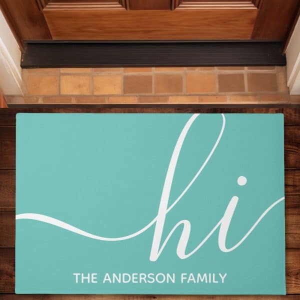 Teal Welcome Mat With The Word Hi In A Stylized White Script Font And The Anderson Family Printed Below.