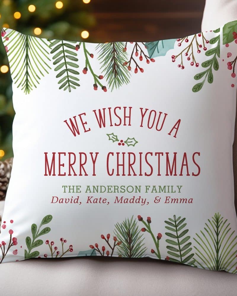 Christmas pillow with watercolor greenery and berries, and the message We Wish You a Merry Christmas, The Anderson Family.