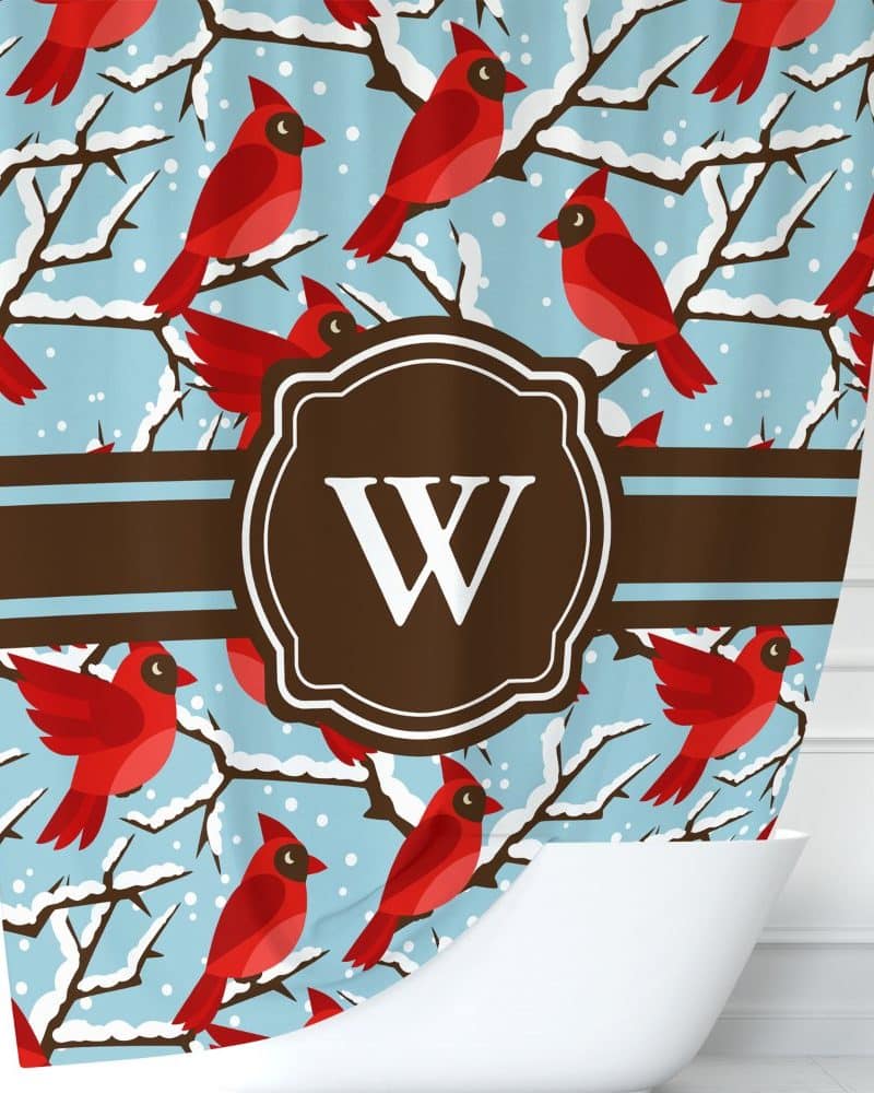 Shower curtain with a winter scene of red cardinals on snow-covered branches and a brown monogram W.