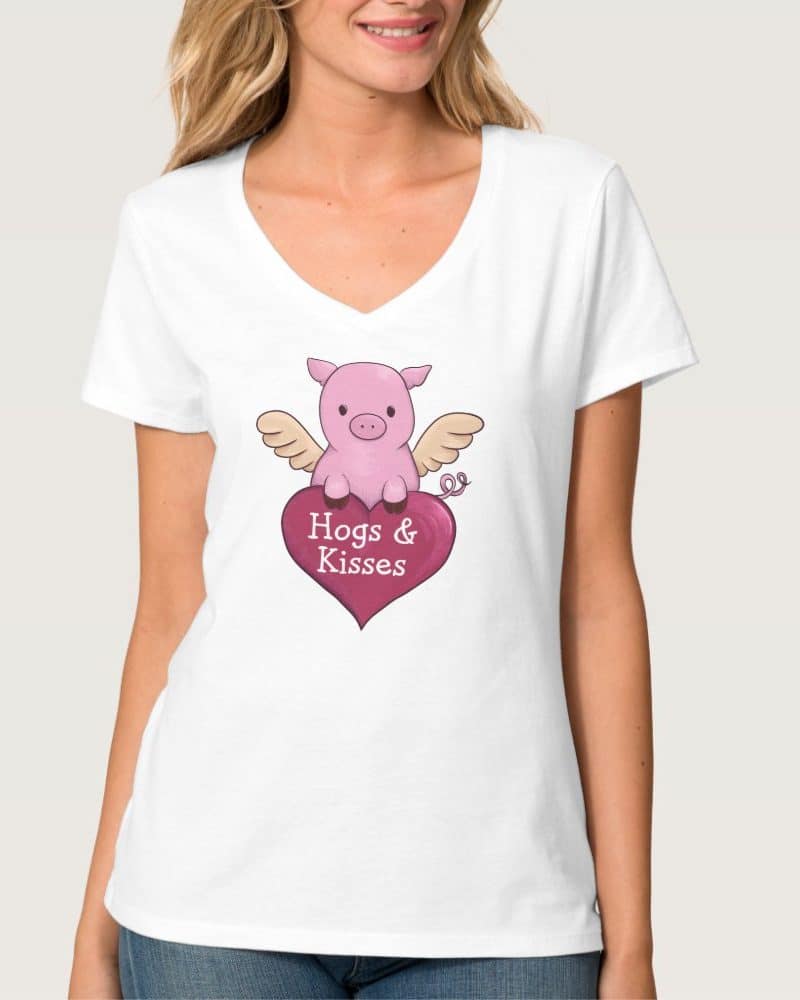 White v-neck t-shirt featuring a pink pig with wings sitting on a heart that says Hogs & Kisses.