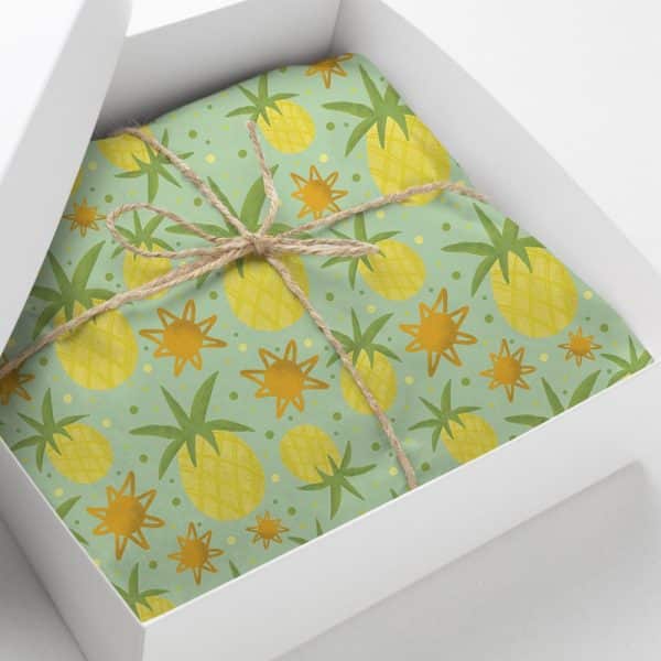 Gift Box With Light Green Wrapping Paper Featuring A Repeating Pattern Of Yellow Pineapples And Orange Stars. The Box Is Tied With Twine.